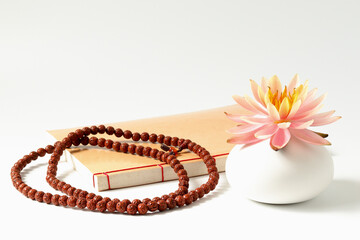 The Buddhist rosary, the Buddhist book and a pink lotus flower in vase