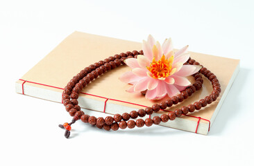 The Buddhist rosary, the Buddhist book and pink lotus flower