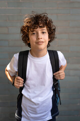 Portrait of a 10 year old schoolboy with backpack on the background of the school wall - concept of back to school for the beginning of the school year © Lomb