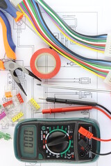 Multimeter and tools for installing an electrical control panel in close-up on an electrical diagram.