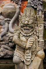 Selective focus stone statue in Temple Batu Bolong near, Tanah Lot, Bali, Indonesia. Carved statue with fine details that stands outside the entrance to Hindu temple as a guardian. Balinese culture.