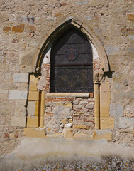 A stained glass window in an old church. A combination of several architectural styles. A replacement window.