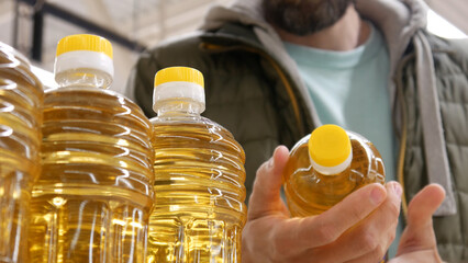 Close-up of beautiful sunflower oil bottles in a store and a male buyer takes one