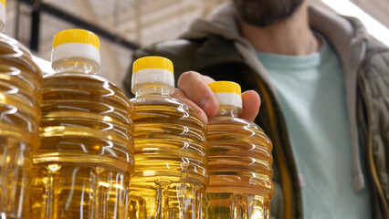 Close-up of beautiful sunflower oil bottles in a store and a male buyer takes one