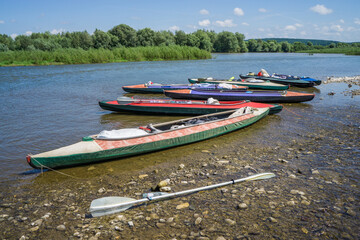 Multicolored kayaks on the bank of a pure mountain river.