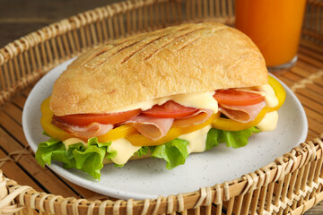 Delicious sandwich with vegetables, ham and mayonnaise served on wicker tray, closeup