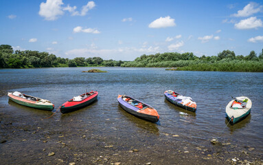 Multicolored kayaks on the bank of a pure mountain river.