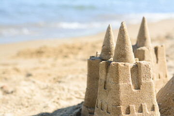 Beach with sand castle near sea on sunny day, closeup. Space for text