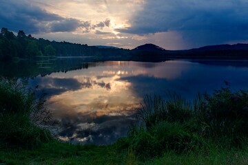 Beautiful sunrise at the lake, Hamr na Jezeře, Czech Republic. Reflection of dramatic sky on water surface.