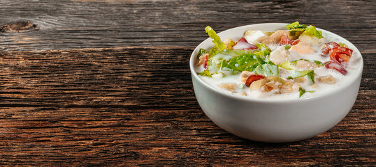 Traditional Russian cold soup okroshka with fresh potato, cucumber, tomato, boiled eggs and kefir. Flat lay, wooden background
