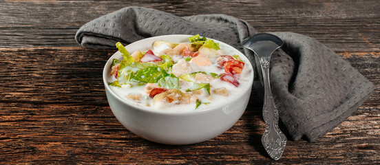 Traditional Russian cold soup okroshka with fresh potato, cucumber, tomato, boiled eggs and kefir. Flat lay, wooden background