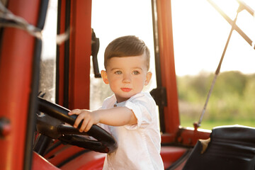 Little boy sitting in a tractor at sunset