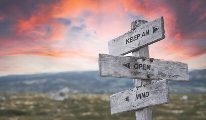 keep an open mind text quote caption on wooden signpost outdoors in nature with dramatic sunset...