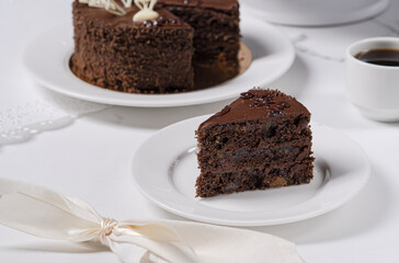A piece of chocolate cake with apricot jam and chocolate cream on a light table.