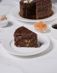A piece of chocolate cake with apricot jam and chocolate cream on a light table.