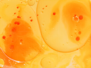 Abstract yellow, orange water bubbles background. .Full frame of the textures formed by the bubbles and drops of oil mixed food coloring with milk in the shape of circle floating on water