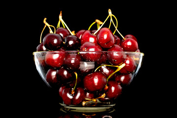 Fototapeta na wymiar Several sweet cherries in a glass bowl, close-up, isolated on a white background.