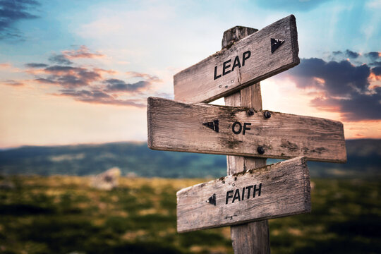leap of faith text quote caption on wooden signpost outdoors in nature. Stock sign words theme.