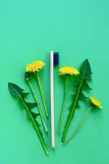 Vertical photo of bunch with yellow flowers of dandelion flowers and leaves and bamboo wooden...
