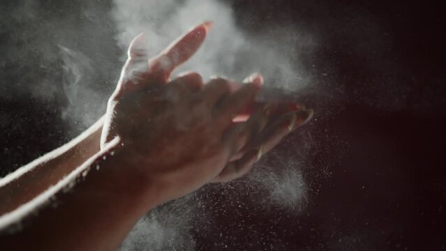 A woman claps her hands with magnesia before doing exercises 