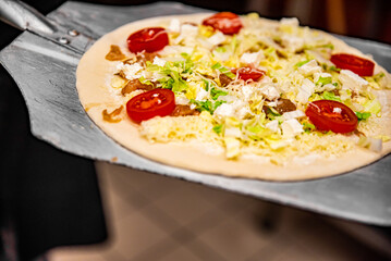 chef baker making pizza at kitchen. Put on landing shovel and send it to the oven.