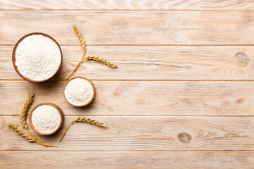 Flat lay of Wheat flour in wooden bowl with wheat spikelets on colored background. world wheat crisis