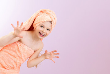 Wrapped in a towel, a little girl looks around the corner after taking a bath and smiles broadly...