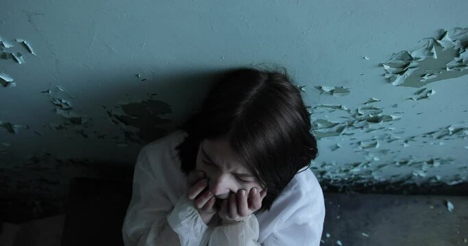 Female drug addict feeling high and crazy. Portrait of hooker girl high on drugs sitting alone on a floor in dirty room. Narcotic addiction and detrimental way of life concept. Young crazy woman.