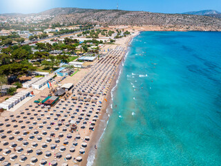 Aerial view of the beach resort at Varkiza, south Athens coast, Attica, Greece, with lined up umbrellas next to the turquoise sea