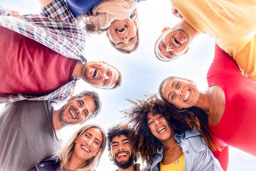 directly below portrait of interracial group of friends posing in the street outdoors laughing and having fun. diverse people celebrating life together enjoying happy holidays. lifestyle concept - obrazy, fototapety, plakaty