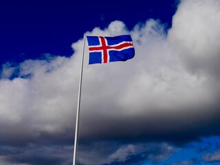Icelandic flag against cloudy sky.