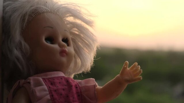 The head of a dreamy doll in the form of a little girl at sunset, close-up