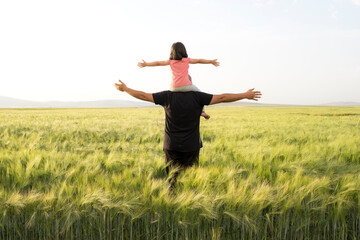 Farmer father, daughter plays on shoulders of farmer father. Happy child and father playing in the...