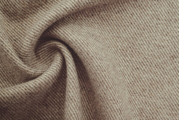 Texture of twisted dense material of brown color. Piece of fabric with waves for tailoring
