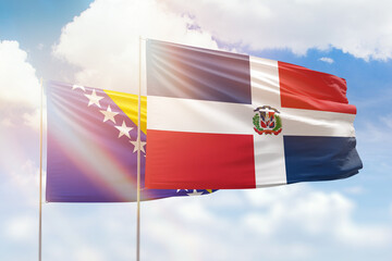 Sunny blue sky and flags of dominican republic and bosnia