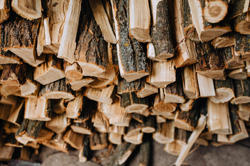 Logs chopped with an ax, dry acacia firewood, spruce stacked in a row close-up.