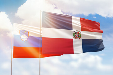 Sunny blue sky and flags of dominican republic and slovenia