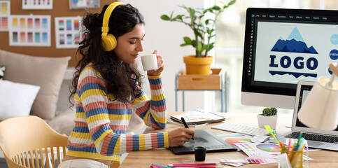 Female graphic designer drinking coffee while working in office