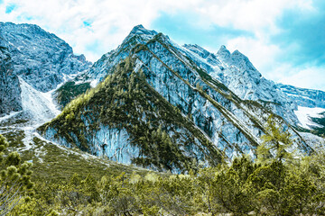 Scenic mountain landscape. Green bushes and pyramid shaped mountain under the blue sky. Particular light. Fresh, sparkling atmosphere.