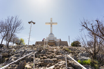 The Cross at the top of the Way of the Cross hill with rocks in the foreground.
