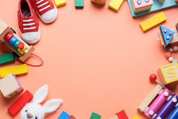 Frame made of educational toys and baby booties on orange background