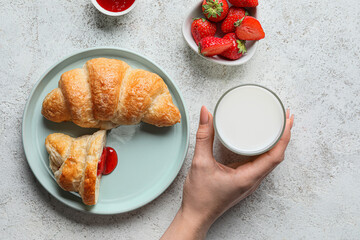 Female hand with glass of milk and plate of tasty croissants on light background - Powered by Adobe
