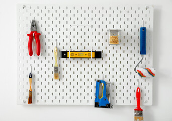 Pegboard with different modern tools on light wall