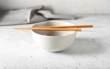 Chinese bowl with chopsticks on light background, closeup