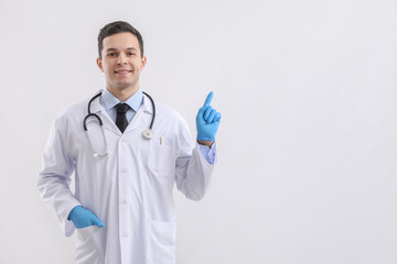 Fototapeta Male doctor in rubber gloves pointing at something on light background obraz