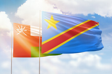 Sunny blue sky and flags of dr congo and oman