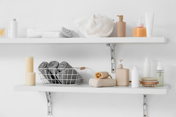 Shelves with bath accessories hanging on light wall