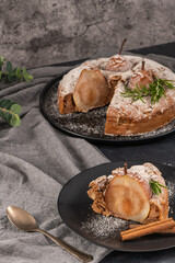 Delicious spice cake with pear, ginger and cinnamon on a dark kitchen counter.