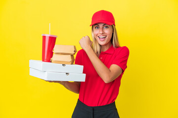 Delivery Uruguayan woman holding fast food isolated on yellow background celebrating a victory