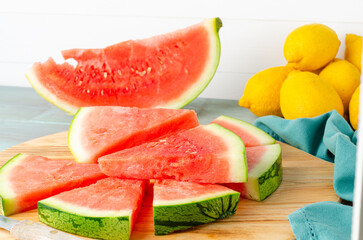 Slices of watermelon and lemons on a wood cutting board and wooden background